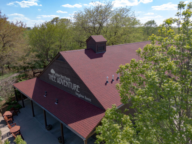 The front entrance viewed from the top of a large wooden building with red shingles