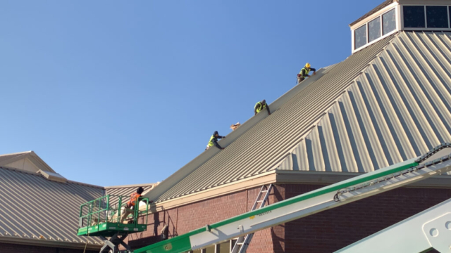 Roofers working on a metal roof on a religious structure